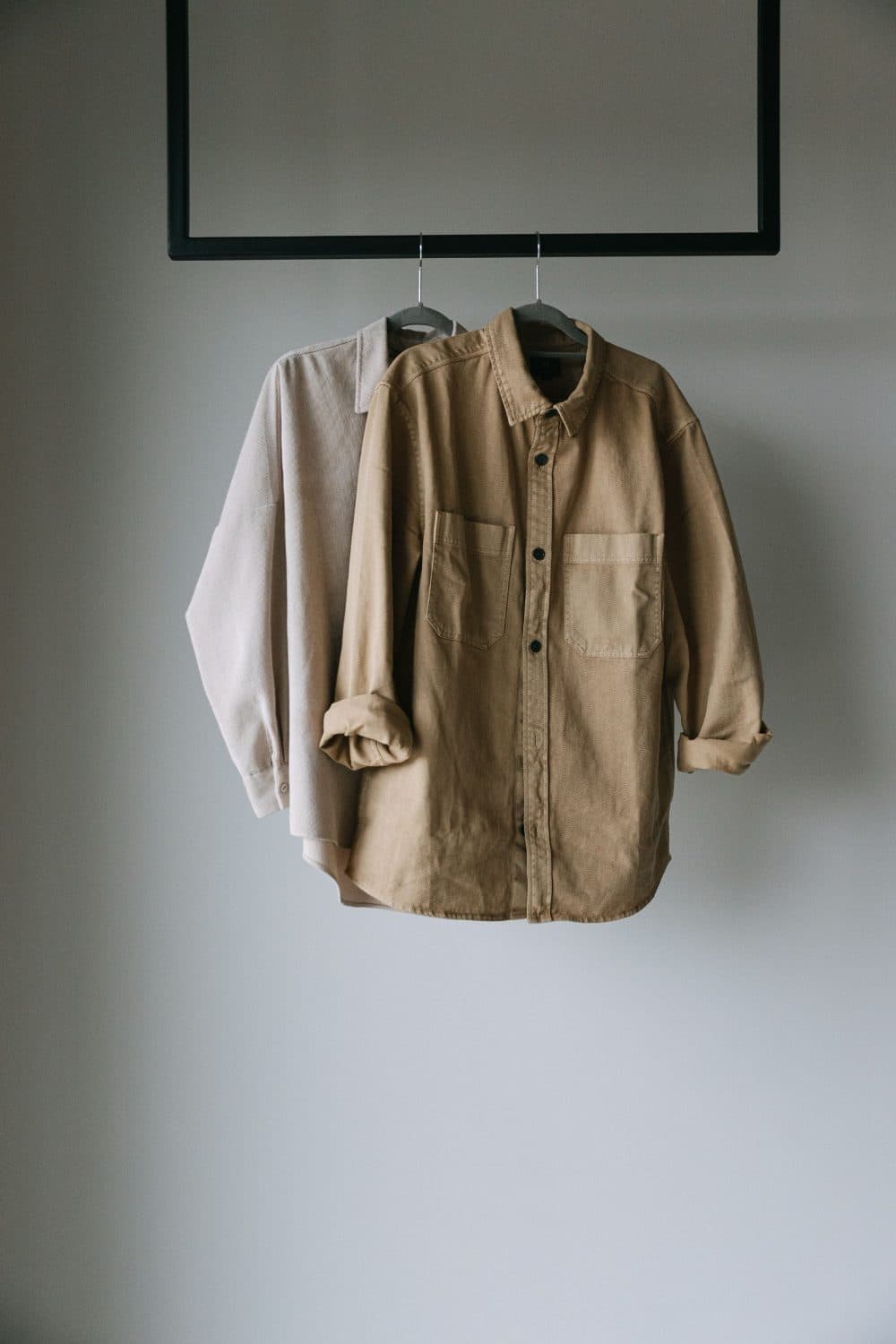 Deux surchemises de coton beige suspendues côte à côte